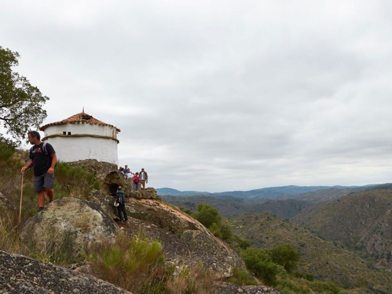 pessoas a caminhar na serra perto de um pombal