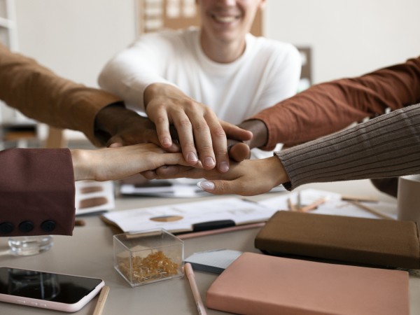pessoas a juntar as mãos em cima de uma mesa